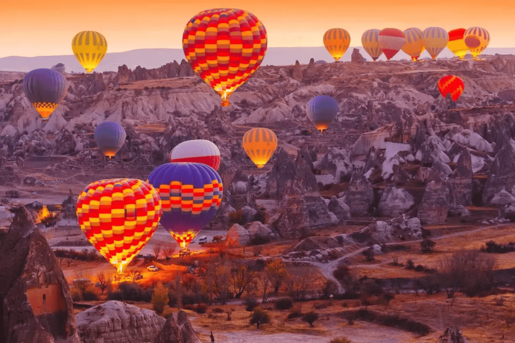 Pemandangan belon udara panas melayang di atas formasi batu cerobong pari-pari Cappadocia sewaktu fajar menyingsing