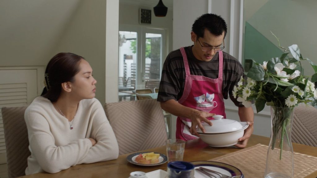 Babak watak Zakief berapron merah jambu menghidang makanan di meja makan kepada Akiera dalam drama Sumpahan Mencintai