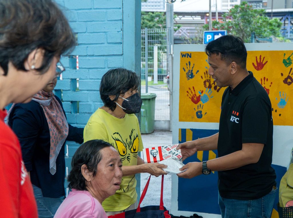 Volunteers distributing the KFC Malaysia face masks and meal packs to a homeless individual at Pusat Khidmat Gelandangan Medan Tuanku