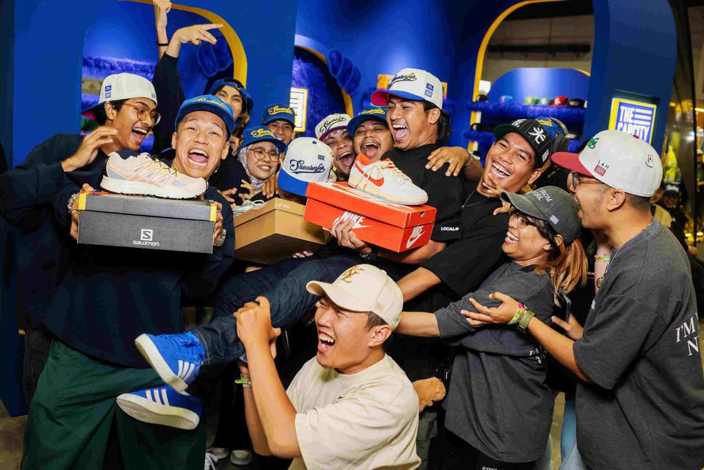 Group of youth attendees cheering and holding sneaker shoe boxes at the LahLahLand lifestyle exhibition booth