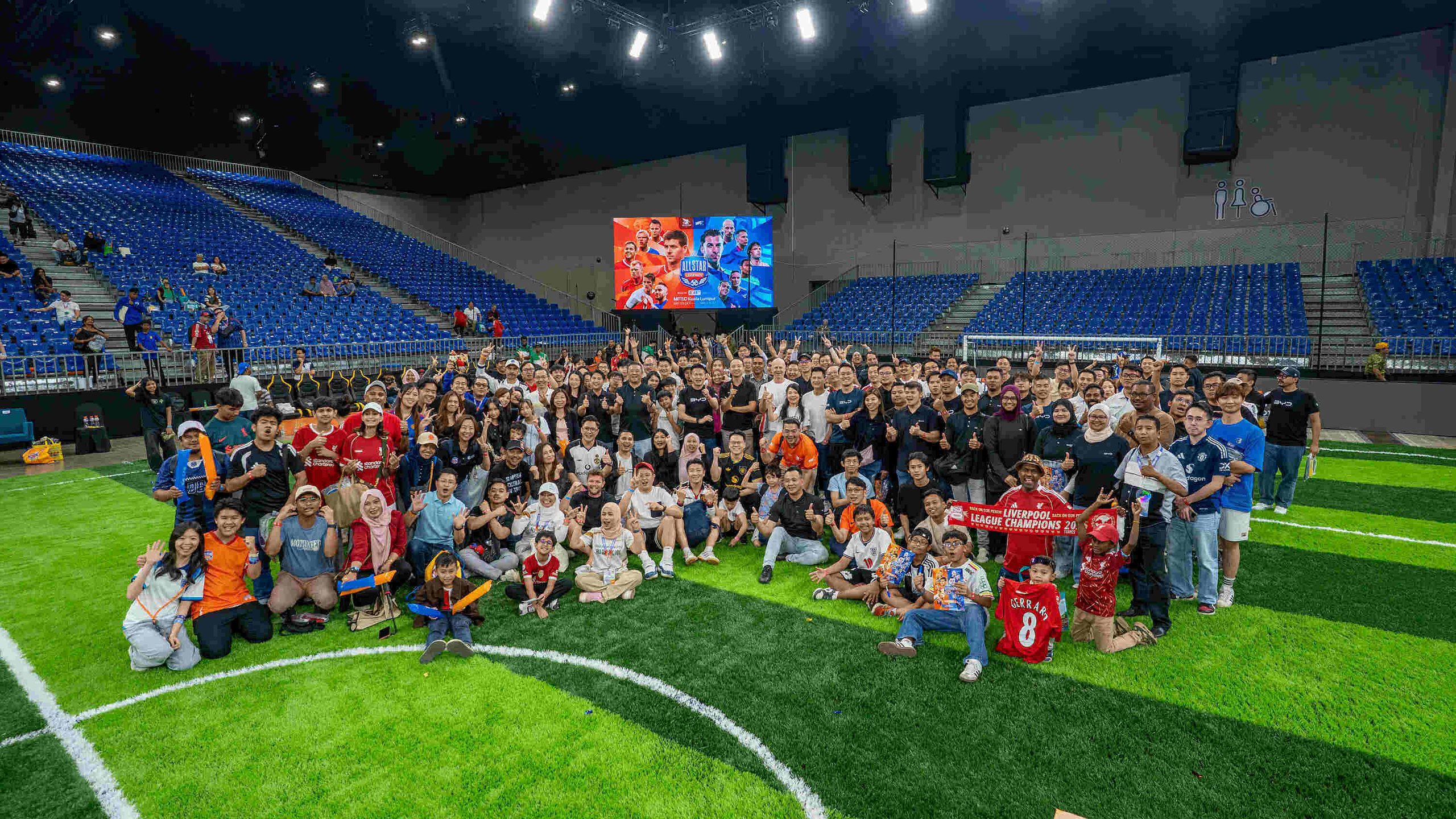Ratusan pemilik kenderaan elektrik BYD bergambar beramai-ramai di atas padang futsal rumput tiruan di dalam dewan MITEC