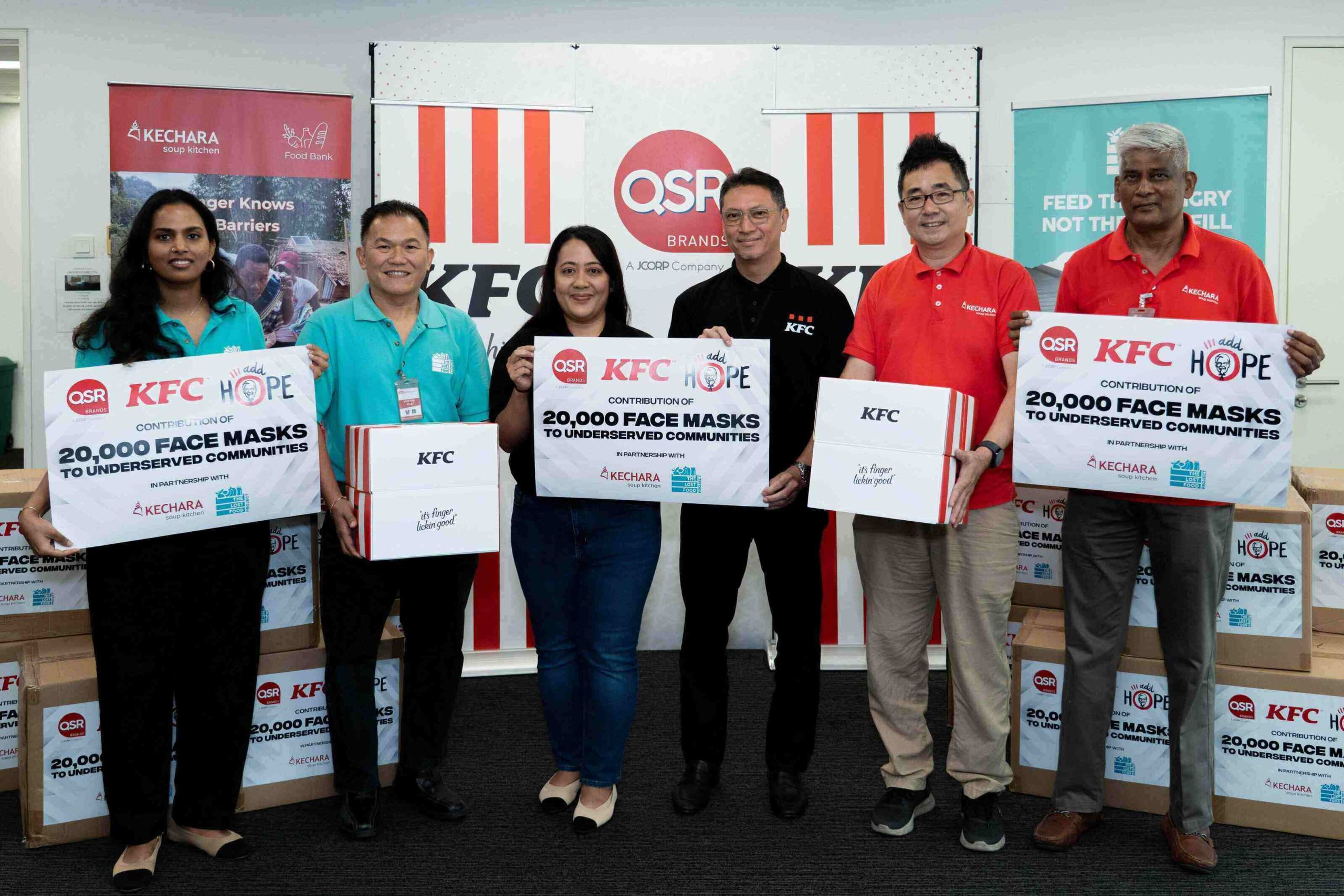 Representatives holding presentation placards for the 20,000 KFC Malaysia face masks donation initiative with NGO partners